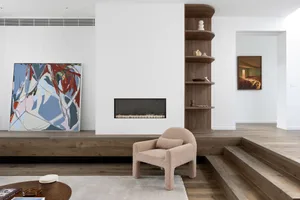 A minimalist living room featuring a wooden floor, a modern fireplace, and abstract art on the walls.