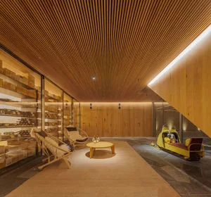 A minimalist wine cellar with wooden walls, featuring shelves filled with bottles of wine and a yellow snowmobile.