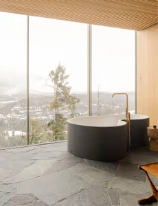 Modern bathroom with stone floor, large glass windows, and a view of a snowy landscape.