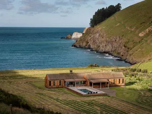 A modern house with a timber exterior overlooking the sea.