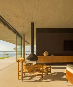 A modern living room with concrete walls and flooring, featuring a hanging fireplace and minimalistic furniture.
