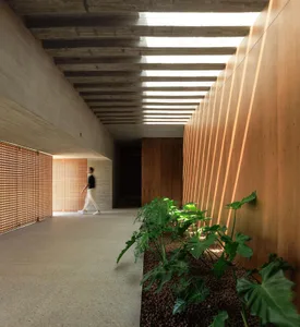 A modern office corridor featuring concrete walls and wooden accents.