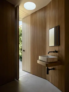 A minimalist bathroom with wooden walls and a floating vanity sink.