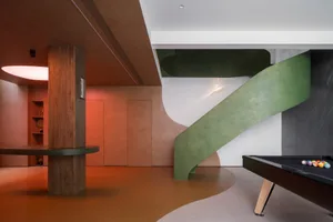 Modern minimalist living room featuring a concrete floor, green staircase, and white walls.