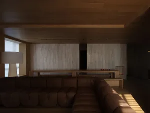 A modern living room featuring wooden furniture and a large sectional sofa positioned in a neutral-toned room.