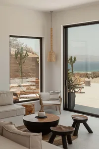 Modern minimalist living room with wood furniture and large windows.