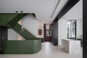 Modern residential interior design featuring marble countertops, black wooden cabinets, and green metal accents