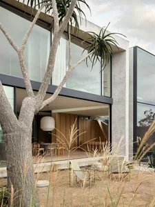 A modern residential living room with concrete, glass, and wooden elements.