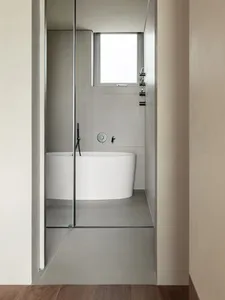 A modern minimalist bathroom with white walls and concrete floor and walls, featuring a white bathtub.
