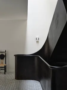 A modern, black metal staircase with curved railings.