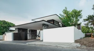 Modern residential building with a minimalist design featuring a concrete facade and large overhanging roof.