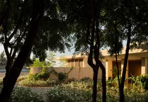 Modern residential architecture with sandstone exterior and lush garden.
