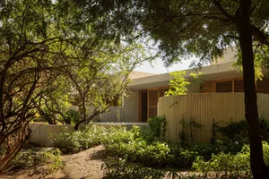 A modern residential exterior with corrugated metal siding and lush greenery.