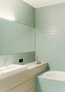 Modern minimalist bathroom featuring green glazed tiles on walls and floor.