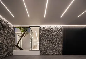 Modern living room with concrete walls and floor, featuring a tree and sleek furniture.