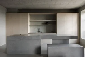 A modern kitchen with concrete countertops and wooden cabinets