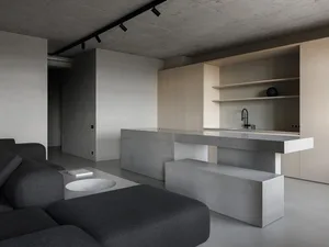 Modern living room with a couch, concrete kitchen counter, and minimalist decor.