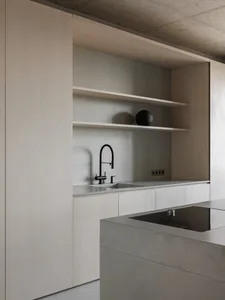 Modern, minimalist kitchen featuring a light wood cabinet with an integrated concrete countertop and minimalist design elemen
