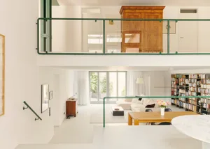 A modern minimalist living room with white concrete and wood elements, including a white sofa, a wooden coffee table, and a w