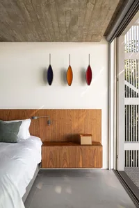 A modern bedroom featuring a floating wood cabinet with a concrete floor.
