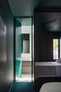 A modern bedroom featuring a glass door leading to an adjacent bathroom with white tiles and wooden cabinetry.