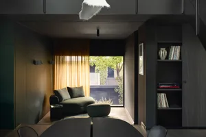 Modern living room with leather sofa, wooden floor, and large windows.
