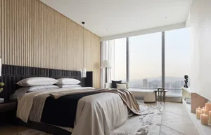 Modern minimalist bedroom with wood paneling, glass windows, and fabric bedding.