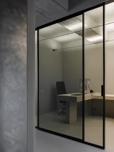 An office with a glass door, concrete walls, and metal accents.