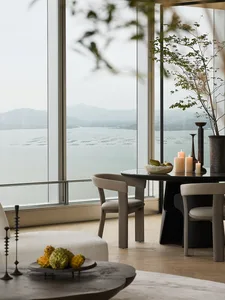 Modern residential space featuring wooden furniture and a scenic view of a lake and mountains.