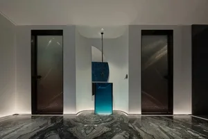 Modern entrance area featuring glass and metal surfaces on a luxurious marble floor