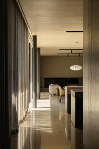 A modern living room with concrete walls, a white sofa, and a pendant light hanging from the ceiling.