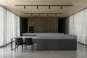 A minimalist kitchen with a granite countertop and black chairs.