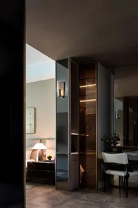 A contemporary bedroom featuring a stylish closet with metallic glass and black materials