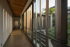 A modern hotel corridor with glass panel walls and a wooden ceiling
