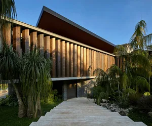 Modern house exterior with a metal facade and tropical landscaping.