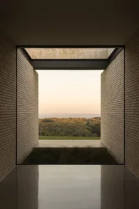 Modern interior design featuring brick and concrete materials, with a view of a forested landscape outside.