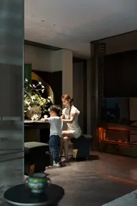 Mother and child arranging flowers in a modern living room setting.