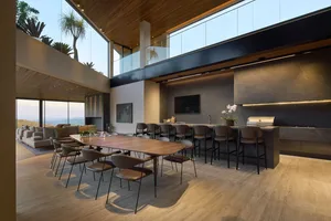 A modern lounge and kitchen featuring marble countertops and wooden dining table.