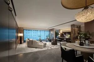 A spacious, modern living room with white marble flooring, a white leather sofa, and a round dining table.
