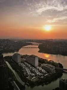Aerial view of a cityscape featuring a river with bridges and buildings at sunset.