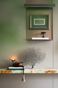 A marble shelf with decorative items including a candle holder with a lit candle, a small bowl, books, a decorative tree scul