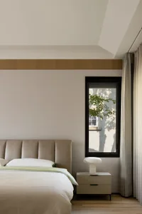 Modern minimalist bedroom with a soft lighting fixture, a spacious bed, and light-colored curtains.