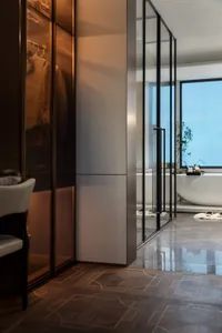 Modern bathroom featuring wooden flooring and a glass-enclosed bathtub.
