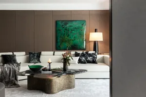 Modern living room featuring a white sectional sofa adorned with black and white floral-patterned pillows, a green vase with 