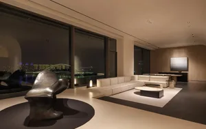 Modern living room with a metallic sculpture, wooden sofa, and glass coffee table.