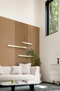 Modern living room featuring a white sofa, wooden and metallic decorative panel, and a green plant.