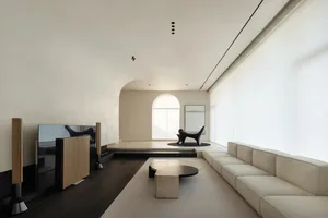 A minimalist living room with a concrete floor, terrazzo table, and a large sofa.