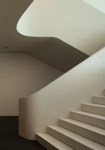 A modern concrete staircase with curved railings and a smooth, minimalist design.