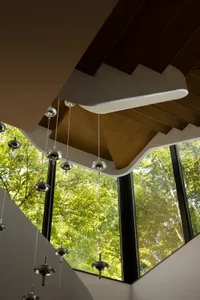 Modern building interior with large glass windows overlooking lush green trees.