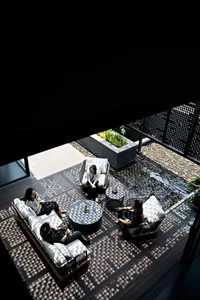 People sitting on white and grey cushioned lounge chairs in a modern patio setting.